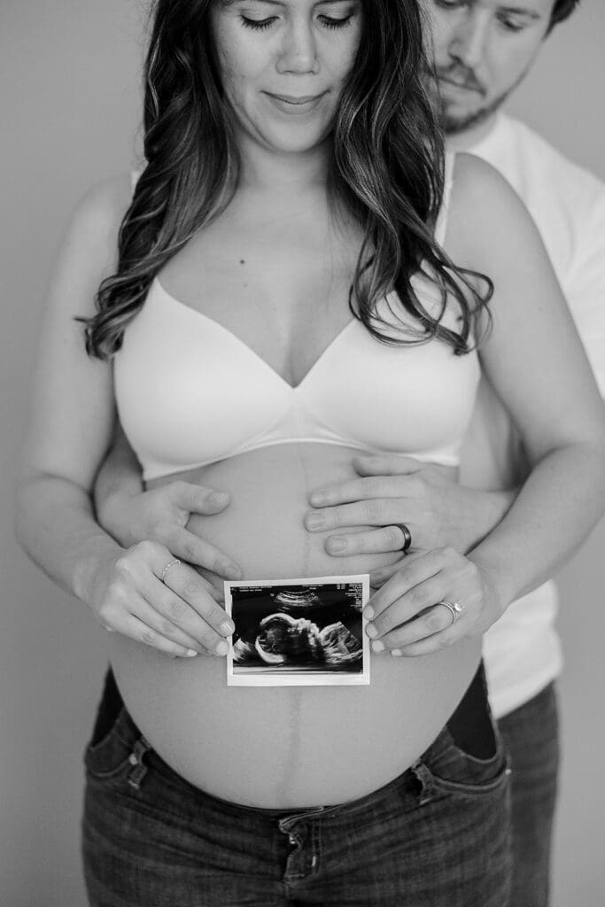 Studio maternity photography in Richmond showing the Holguins with flowers, ultrasound pictures and simple elegant backdrops.