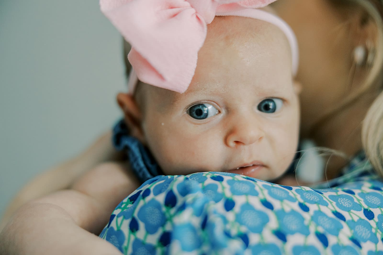 In-home newborn family photography session with parents and siblings snuggling their new baby on the couch.