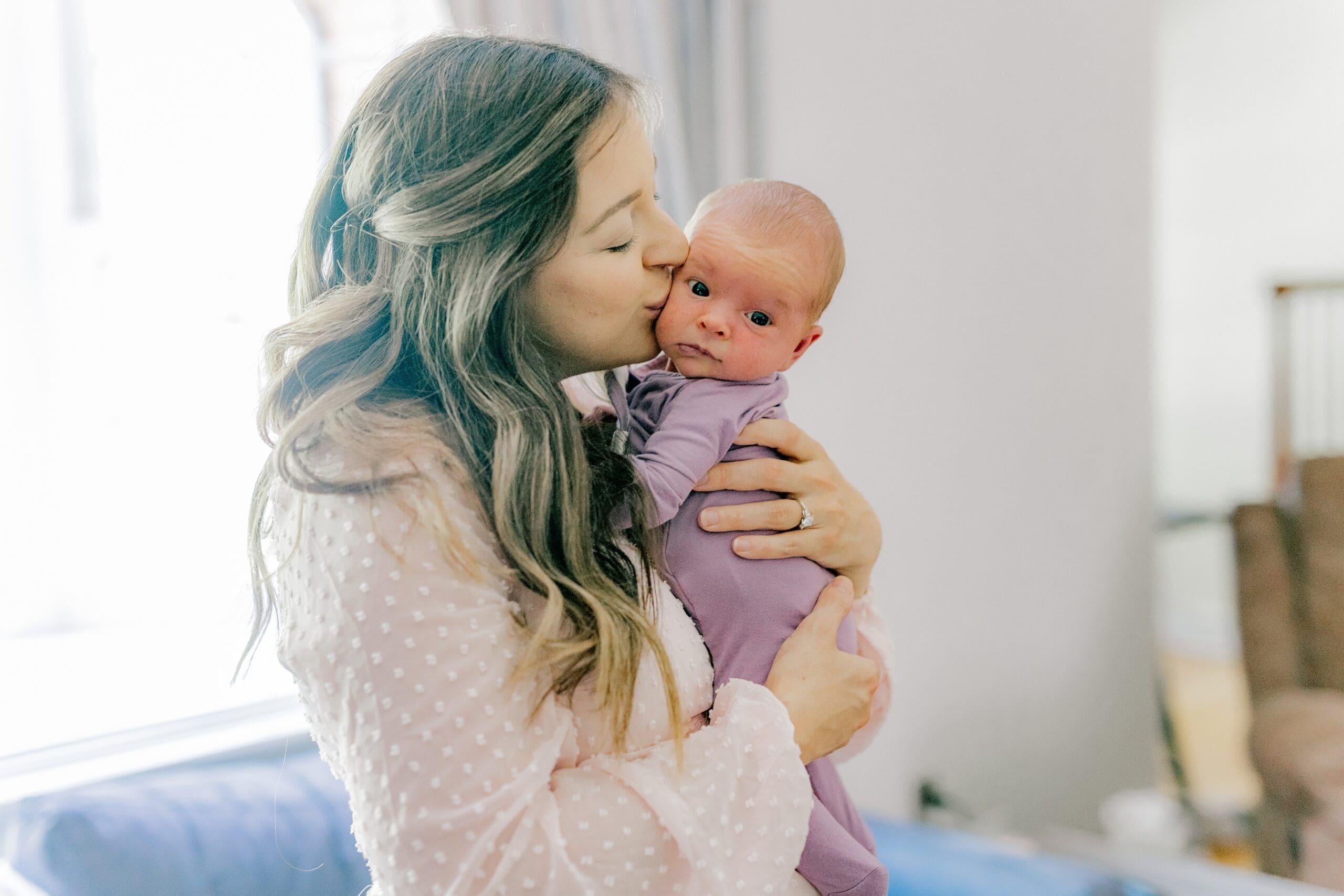 A mom poses with her baby during their newborn photo prep.