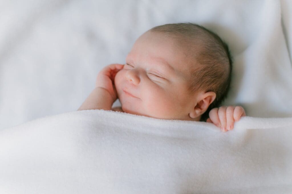 A baby poses sleepily during his newborn photo session