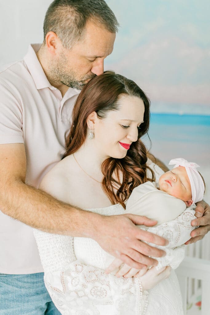 Baby Ember cuddles with parents during her in-home newborn photography session.