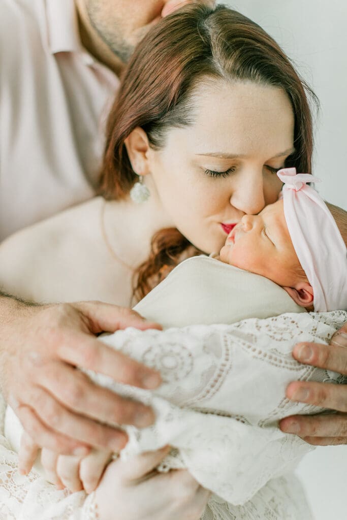 Baby Ember poses with mom and dad during her in-home newborn photography session.