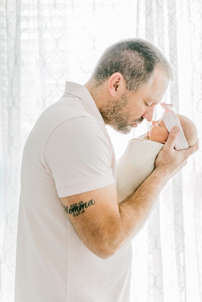 Baby Ember poses in front of a window during her in-home newborn photography session.