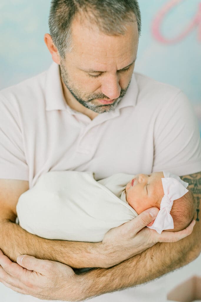 Baby Ember poses with her dad during her in-home newborn photography session.