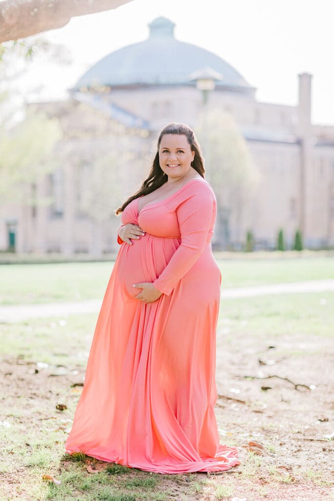 VMFA spring maternity photography featuring Shannon in a flowing pink dress with cherry blossoms and grand architecture.