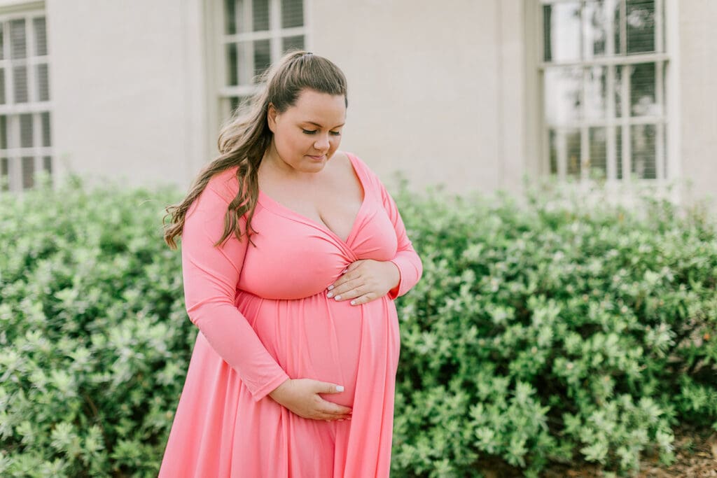 VMFA spring maternity photography featuring Shannon in a flowing pink dress with cherry blossoms and grand architecture.