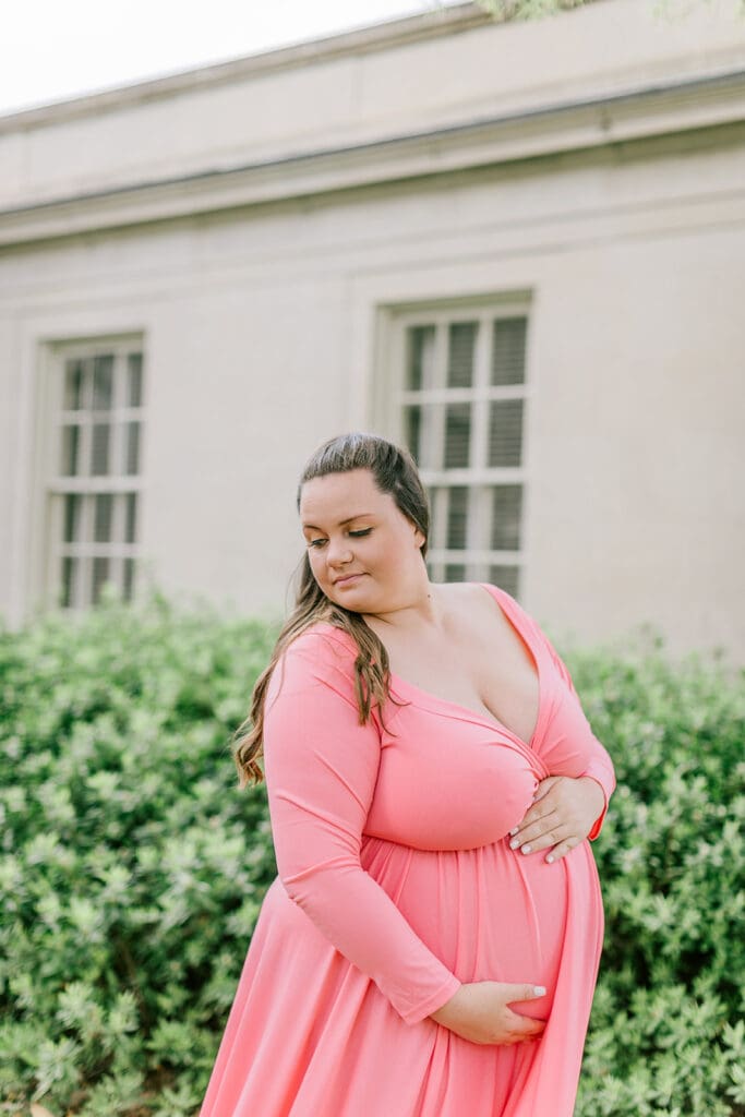 VMFA spring maternity photography featuring Shannon in a flowing pink dress with cherry blossoms and grand architecture.