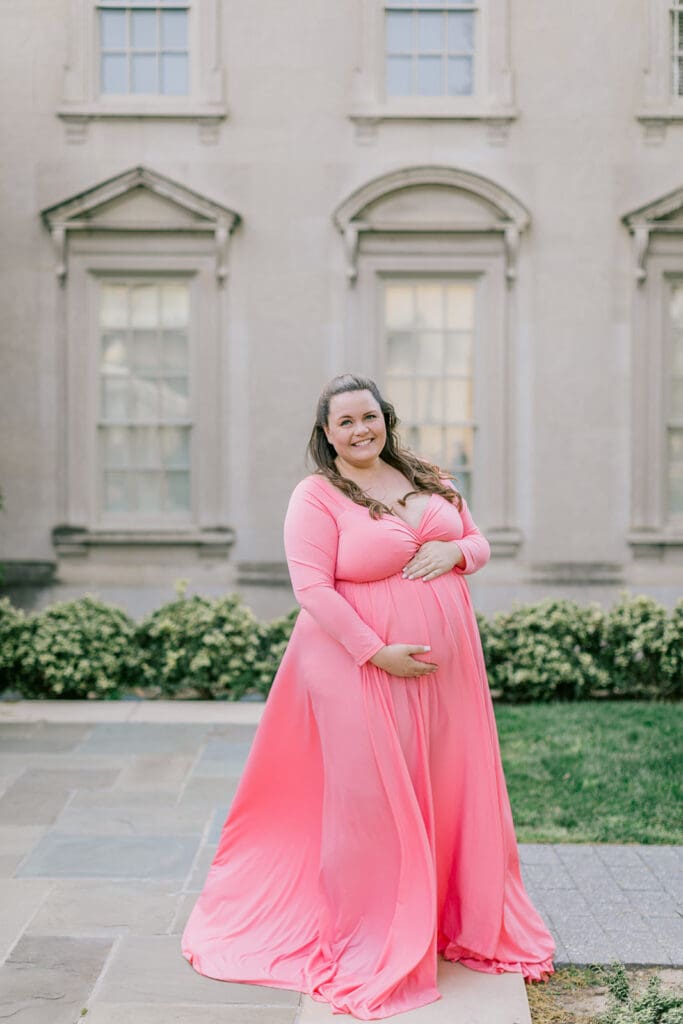 VMFA spring maternity photography featuring Shannon in a flowing pink dress with cherry blossoms and grand architecture.