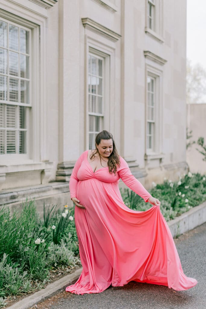 VMFA spring maternity photography featuring Shannon in a flowing pink dress with cherry blossoms and grand architecture.