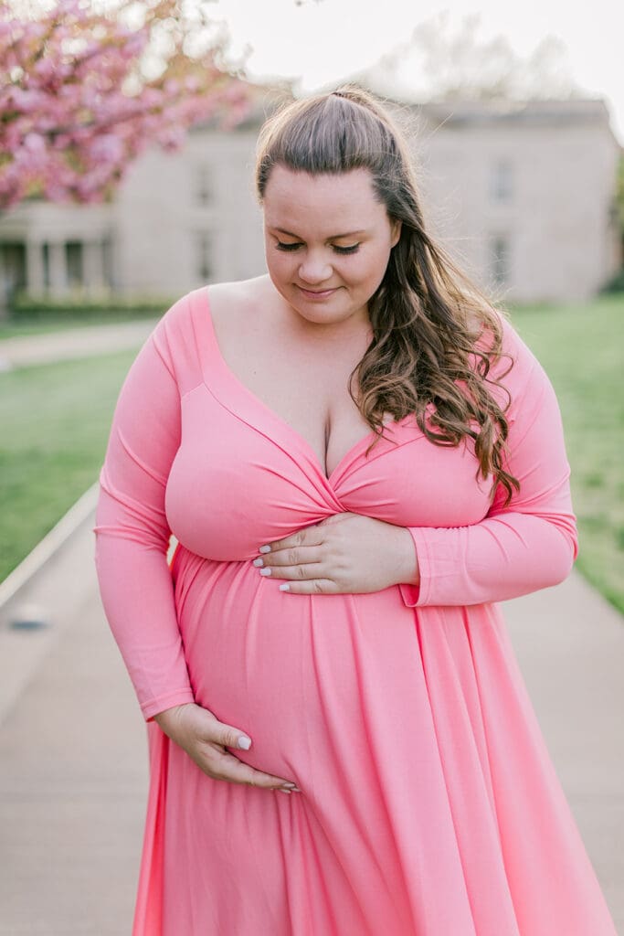 VMFA spring maternity photography featuring Shannon in a flowing pink dress with cherry blossoms and grand architecture.