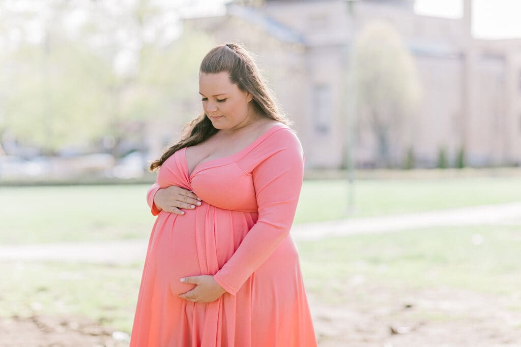 VMFA spring maternity photography featuring Shannon in a flowing pink dress with cherry blossoms and grand architecture.