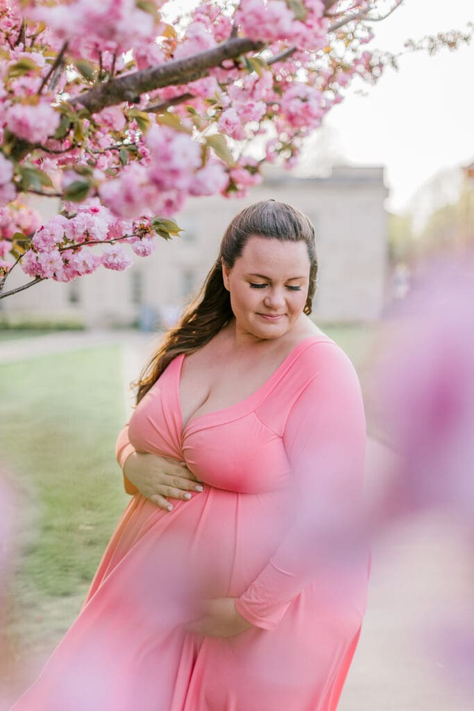 VMFA spring maternity photography featuring Shannon in a flowing pink dress with cherry blossoms and grand architecture.v