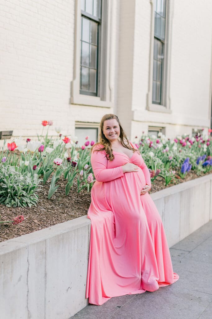 VMFA spring maternity photography featuring Shannon in a flowing pink dress with cherry blossoms and grand architecture.