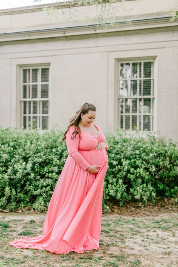 VMFA spring maternity photography featuring Shannon in a flowing pink dress with cherry blossoms and grand architecture.