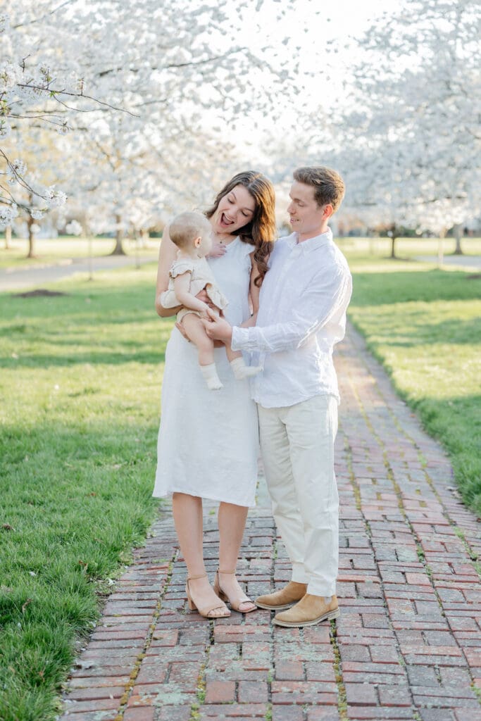 Family poses with their baby girl during their family photography session in the cherry blossoms in Richmond.