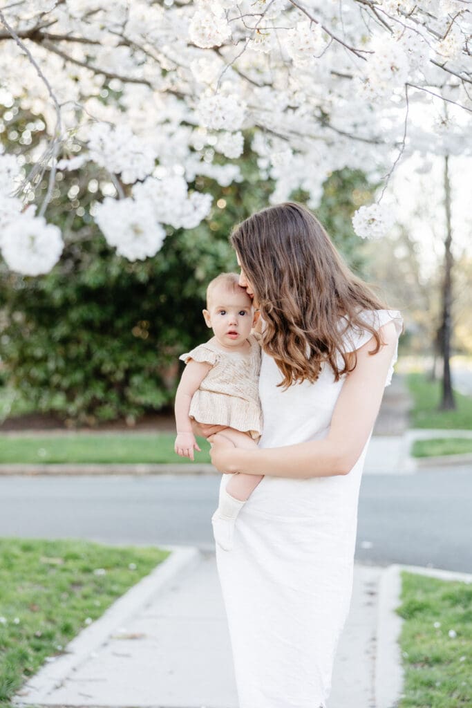 Family poses with their baby girl during their family photography session in the cherry blossoms in Richmond.