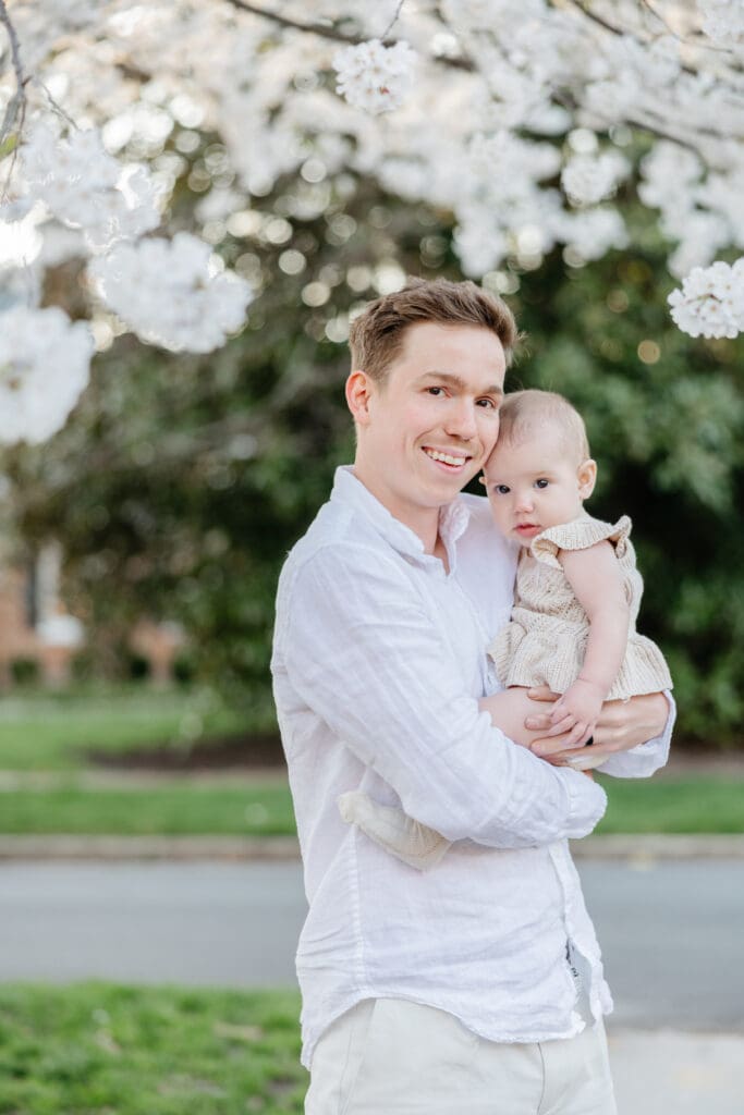 Family poses with their baby girl during their family photography session in the cherry blossoms in Richmond.