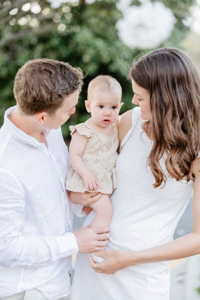 Family poses with their baby girl during their family photography session in the cherry blossoms in Richmond.