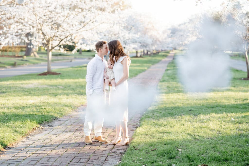 Family poses with their baby girl during their family photography session in the cherry blossoms in Richmond.