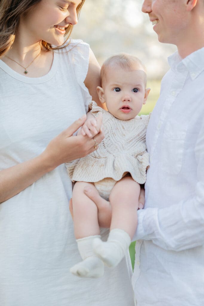 Family poses with their baby girl during their family photography session in the cherry blossoms in Richmond.