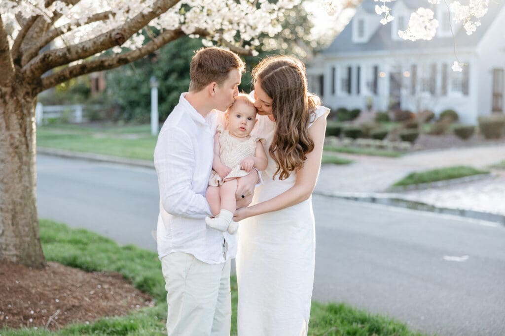 Family poses with their baby girl during their family photography session in the cherry blossoms in Richmond.