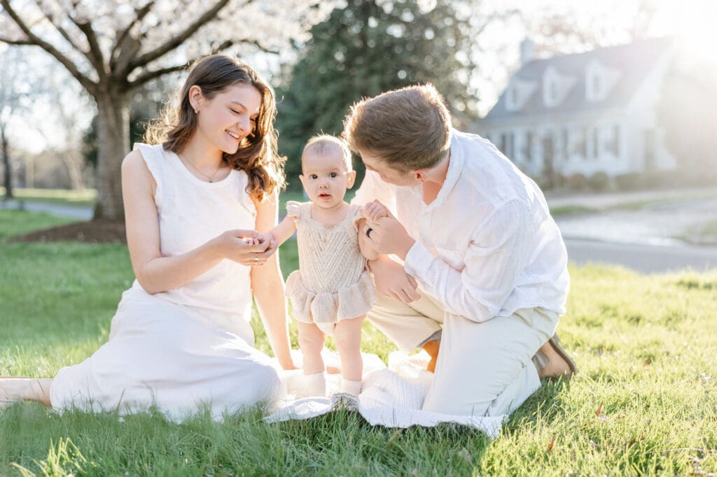 Family poses with their baby girl during their family photography session in the cherry blossoms in Richmond.