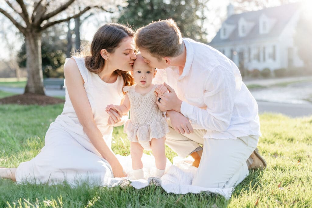 Family poses with their baby girl during their family photography session in the cherry blossoms in Richmond.