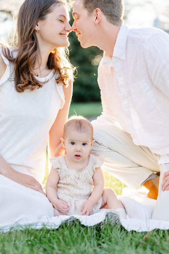 Family poses with their baby girl during their family photography session in the cherry blossoms in Richmond.