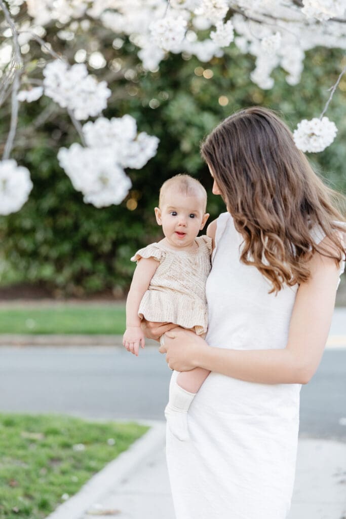 Family poses with their baby girl during their family photography session in the cherry blossoms in Richmond.