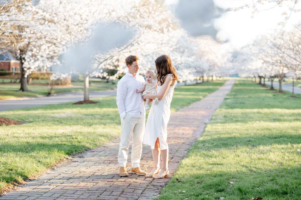 Family poses with their baby girl during their family photography session in the cherry blossoms in Richmond.