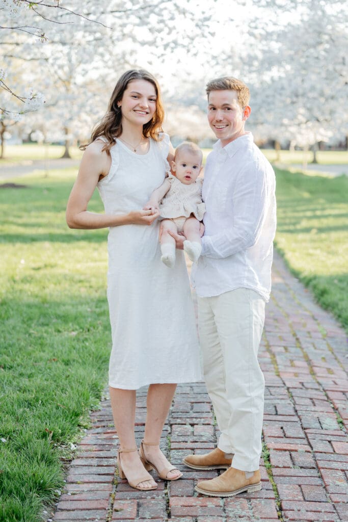 Family poses with their baby girl during their family photography session in the cherry blossoms in Richmond.