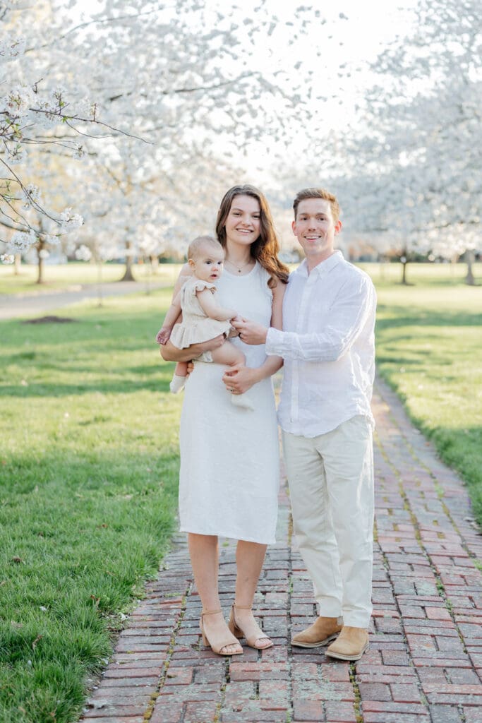Family poses with their baby girl during their family photography session in the cherry blossoms in Richmond.
