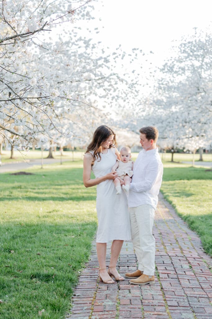 Family poses with their baby girl during their family photography session in the cherry blossoms in Richmond.