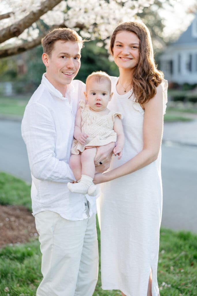 Family poses with their baby girl during their family photography session in the cherry blossoms in Richmond.
