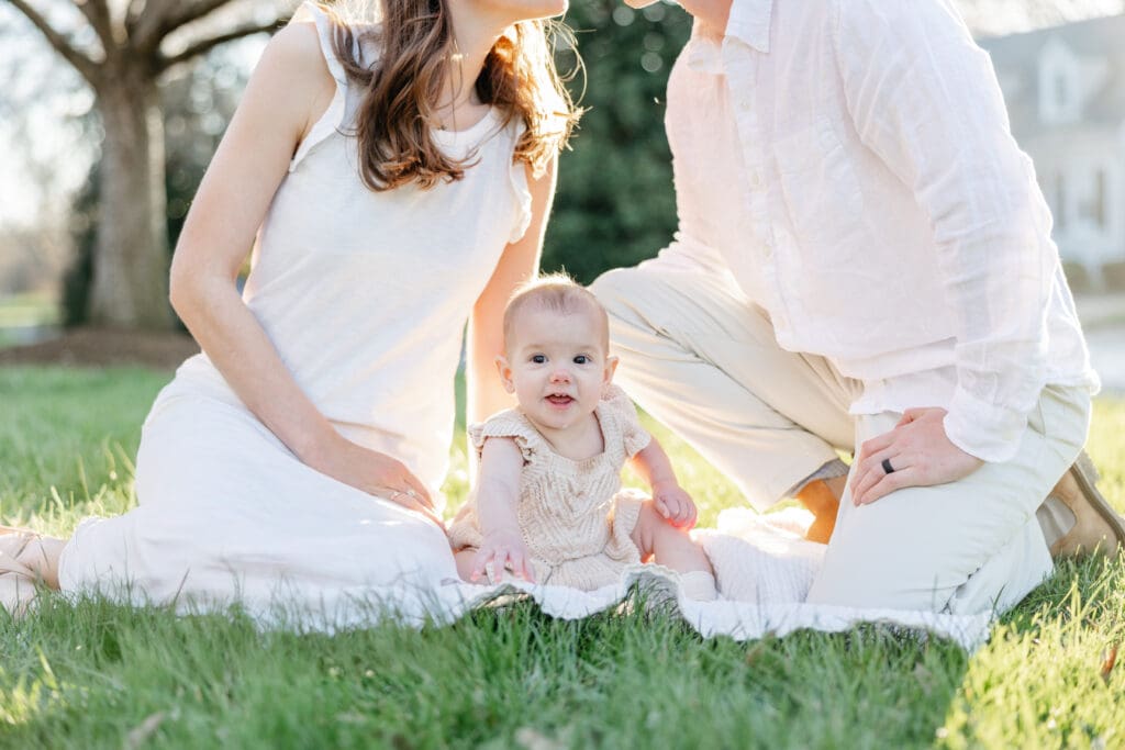 Family poses with their baby girl during their family photography session in the cherry blossoms in Richmond.