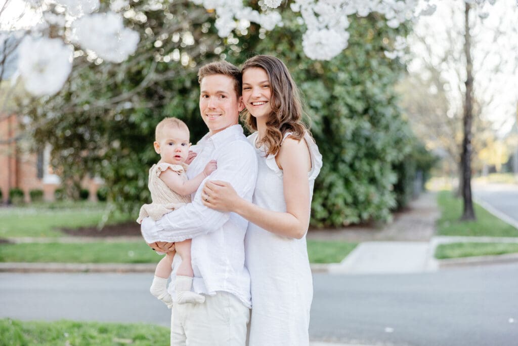 Family poses with their baby girl during their family photography session in the cherry blossoms in Richmond.