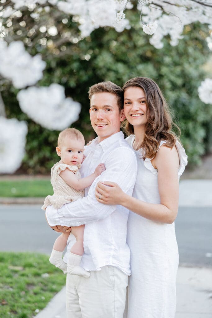 Family poses with their baby girl during their family photography session in the cherry blossoms in Richmond.